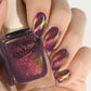 Hand model holding Cirque Colors Fool’s Paradise nail polish bottle with amethyst purple magnetic multichrome polish on nails, featuring rose pink, orange, gold, and green shimmer effects