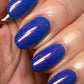 cirque colors cobalt blue shimmer nail polish on hand model close up 