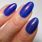 cobalt blue shimmer nail polish on hand model close up 